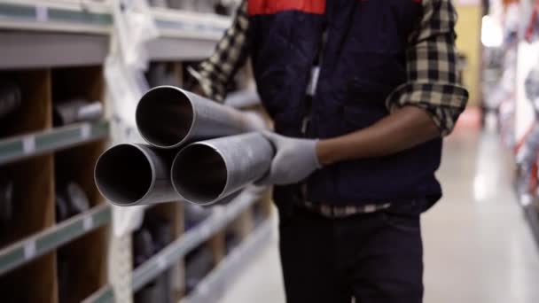 Felismerhetetlen munkás vízvezetékkel sétál vízvezeték- vagy vaskereskedésben, vágva — Stock videók