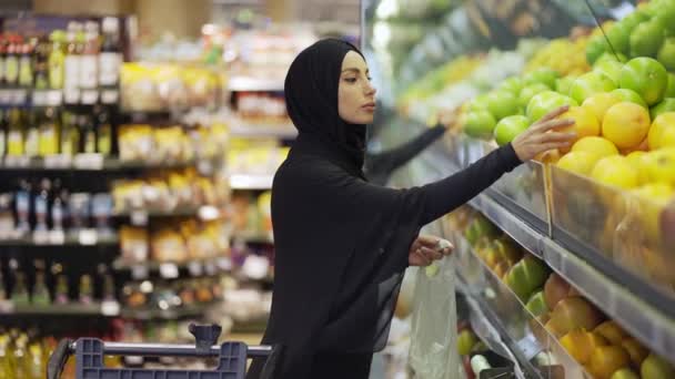 Müslüman kadınlar market alışverişi yapıyor, raftan meyve alıyorlar. — Stok video