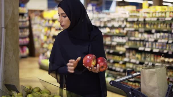 Femme musulmane faisant des courses, prenant des pommes rouges de l'allée des fruits — Video