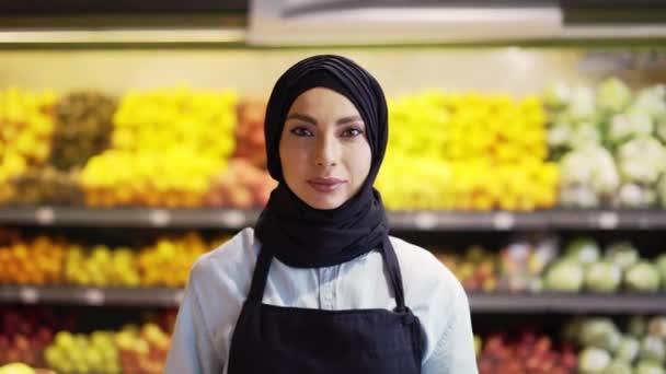 Portrét ženy v hidžábu stojící s košíkem čerstvé zeleniny a zeleně v supermarketu — Stock video