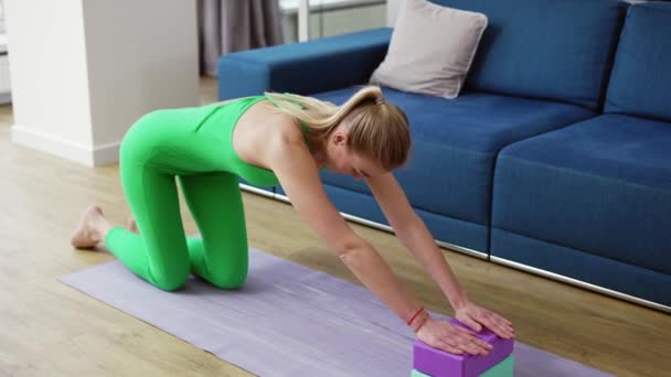 Kobieta rozciąganie kręgosłupa z bloków jogi w salonie w domu — Wideo stockowe