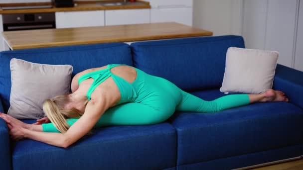 Mulher praticando ioga split pose Hanumanasana no sofá — Vídeo de Stock