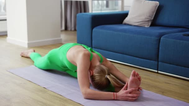 Vrouw oefenen yoga split pose Chanoemanasana thuis — Stockvideo