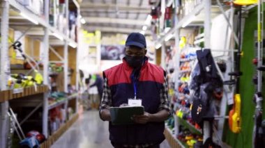 Odaklanmış adam tamir malzemeleri dükkanında çalışıyor, maske takıyor.