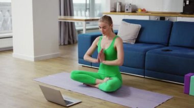 Spor giyinen kadın videoda konuşuyor. Yoga minderlerine otur namaste 'de selamla.
