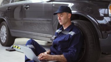 Otomatik onarım servisinde dizüstü bilgisayarda çalışan araba tamircisi