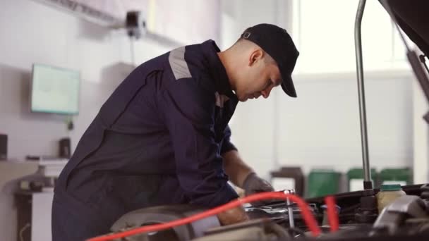 Automechaniker mit Schraubenschlüssel zur Reparatur des Motors im Autoservice — Stockvideo