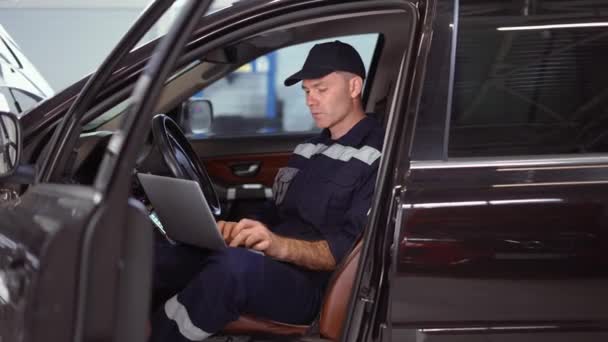 Mechanik pracující na notebooku v autoopravně uvnitř vozu — Stock video