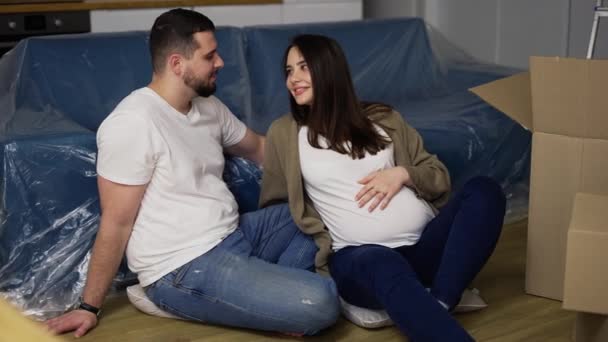 Glückliches junges Paar auf dem Fußboden im Wohnzimmer seiner neuen Wohnung — Stockvideo