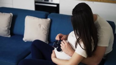 Güzel hamile kadın ve kocası karnında bebek ayakkabıları taşıyorlar.