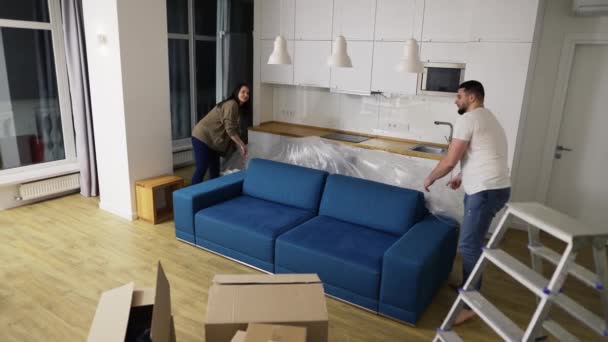 Cuplu căsătorit îndepărtând acoperirea de pe canapea în noul lor apartament — Videoclip de stoc
