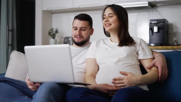 Прекрасна вагітна жінка і чоловік дивиться комедійний фільм на ноутбуці — стокове відео