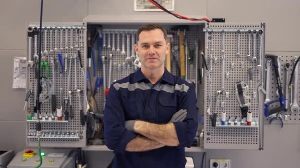 Portret van een automonteur in een autowerkplaats in uniform met apparatuur op de achtergrond — Stockvideo