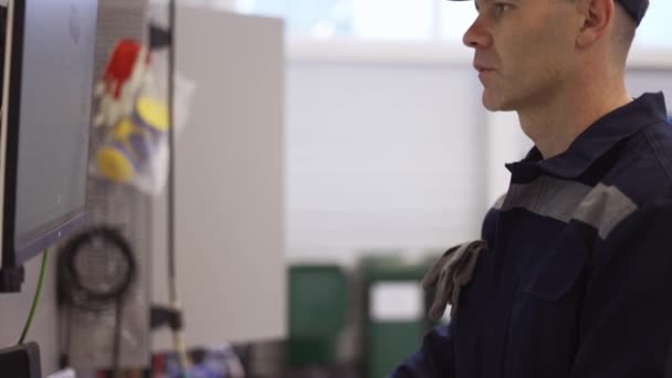 Hombre en el taller en uniforme de uso de la computadora para su trabajo para la fijación de coches rotos — Vídeos de Stock