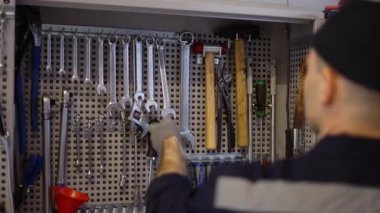 Bir araba tamircisi elinde anahtarlarla tezgahın yanında duruyor. Gereken büyüklükte, ağır çekimde.