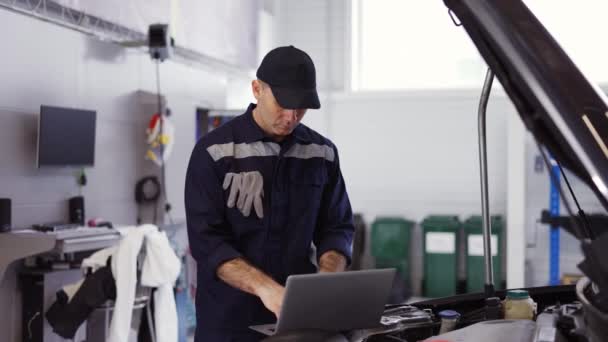 Retrato de mecânico usa um laptop durante a realização de teste de diagnóstico no motor — Vídeo de Stock