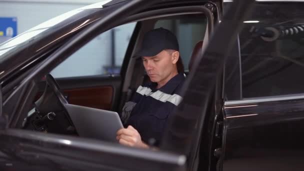 Mecânico de carro trabalhando no laptop no serviço de reparação de automóveis dentro do carro — Vídeo de Stock