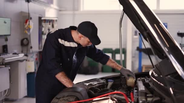 Mekaniker i en bilverkstad kontrollerar motorn manuellt — Stockvideo