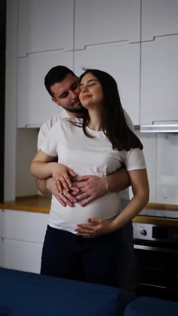 Ευτυχισμένος σύζυγος που κρατά την κοιλιά της εγκύου γυναίκας στο σπίτι — Αρχείο Βίντεο