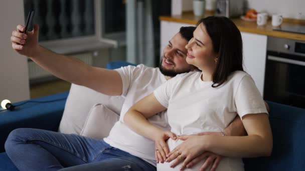 Felice uomo e sua moglie incinta prendendo selfie da smartphone a casa — Video Stock