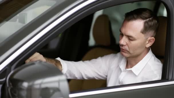 Hombre sentado dentro del vehículo en la concesionaria de automóviles — Vídeo de stock