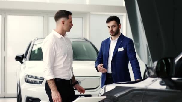 Agent rozmawiający z klientem stojącym przy otwartej masce samochodu — Wideo stockowe