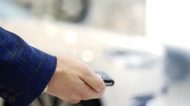 Adam araba galerisinde uzaktan kumandayla arabayı açar.