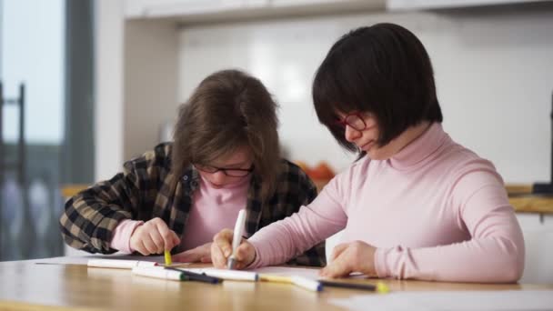 Dos chicas dibujan con plumas de colores en casa. Comunicación de los niños con discapacidad — Vídeos de Stock