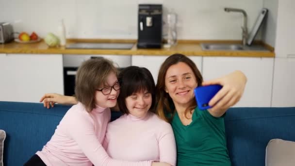 Kvinna tar en selfie med sina döttrar med ner syndrom sitter på soffan i vardagsrummet — Stockvideo