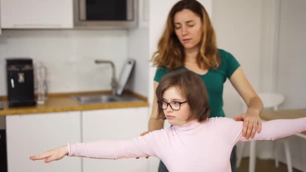Девушка с синдромом Дауна и ее мама практикуют йогу дома — стоковое видео