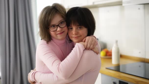 Down sendromlu iki tatlı kız evde birbirlerine sarılıyorlar. — Stok video