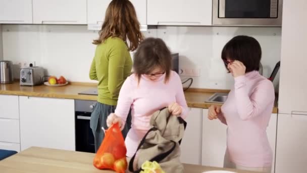 Síndrome de Down niñas con madre en la cocina después de ir de compras — Vídeos de Stock