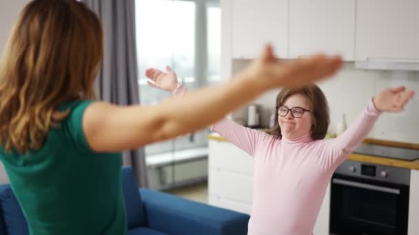 Girl with down syndrome and her mom practicing yoga position at home, tree position — Stock video