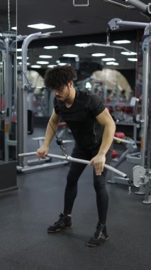 Genç adam spor salonunda sırt sümüklü böcekler için yan çekme egzersizi yapıyor..