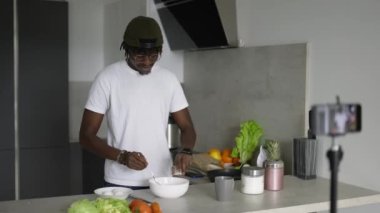 Afrikalı adam mutfak kayıtlarında cep telefonuyla duruyor. Sabahları yeni yemek video bloğu, yavaş çekim..