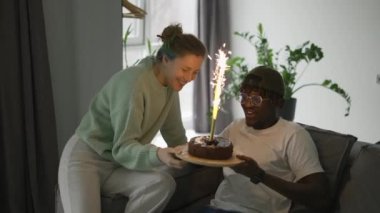 Genç kadın kocasına büyük, parlak mumlu doğum günü pastasını getirdi..