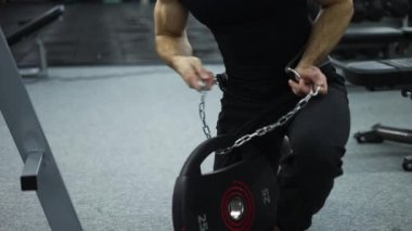 Çelik zincir ve halter kemeri tutan güçlü sporcu spor salonunda sıkı çalışmaya gidiyor..