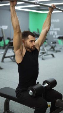 Vertical vide of male training back and hands muscles doing pulls weight exercise in a gym
