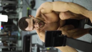 Shirtless athlete training rowing machine exercise intense endurance workout, slow motion.