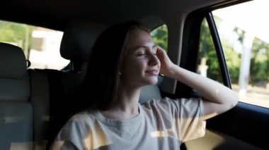 Young woman sitting in car passenger seat looking out window, enjoying ride.