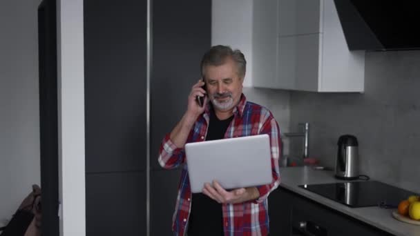 Bearded Old Man Using Laptop Kitchen Talking Phone Same Time — Video Stock