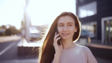 Cep telefonuyla konuşan mutlu bir kadın, arka planda lensler, yavaş çekim..