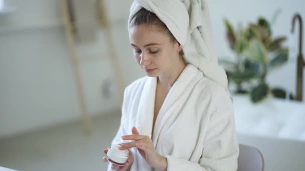 Young Woman White Bathrobe Towel Head Applies Moisturizer Cream Her — 图库视频影像