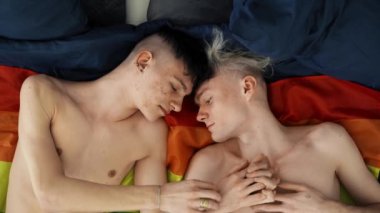 Two gay men lovers laying side by side on flag, LGBT concept, slow motion.