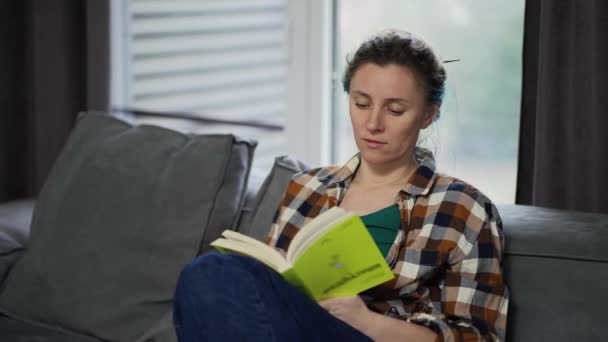 Молодая Красивая Женщина Читает Книгу Сидя Дома Диване — стоковое видео