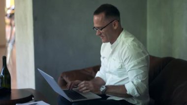 An businessman working on laptop computer. Male professional typing on laptop keyboard at caffe. Portrait of positive business man looking at laptop screen indoors.