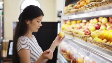 An Asian shop visitor chooses fruits. Hold a basket in your hands. Choice of products in the store.