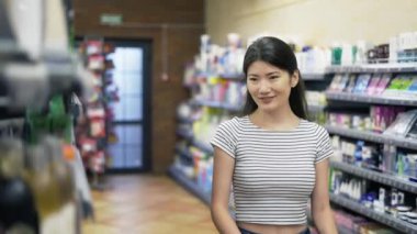 Covid 19 salgını sırasında alışveriş. Kafkas maskeli kadın dükkandaki güzellik ürünlerini karşılaştırıyor..