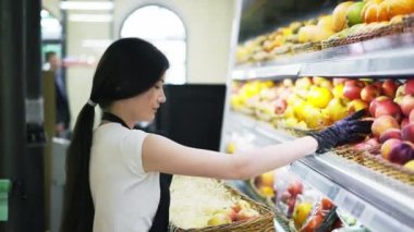 Asian girl worker puts goods on the shelf. Filling shelves with goods. Shop work.