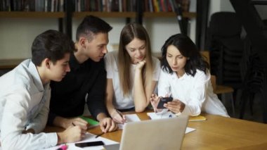 Bir grup öğrenci, lise öğrencileri üniversite kütüphanesinde toplanıyor, konuları tartışıyor, yaratıcı görevler üzerinde birlikte çalışıyor, üniversite sınavlarına hazırlanıyor ya da sınavlar dizüstü bilgisayar kullanıyor. Eğitim, eğitim, modern teknoloji konsepti.